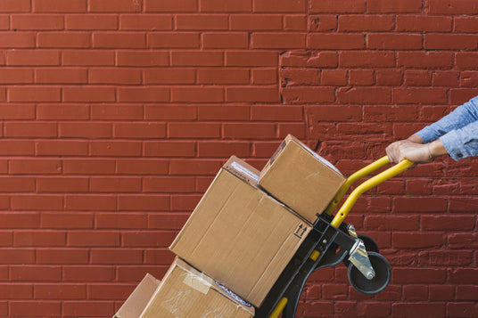 This is an image of a brick wall with someone pulling a sack truck full of parcels